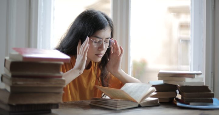 female student suffering from headache in library